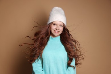 Beautiful teenage girl with freckles in hat on brown background