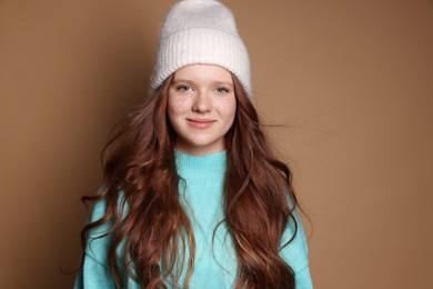 Photo of Beautiful teenage girl with freckles in hat on brown background