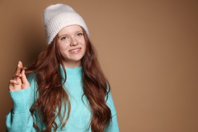 Beautiful teenage girl with freckles in hat on brown background, space for text