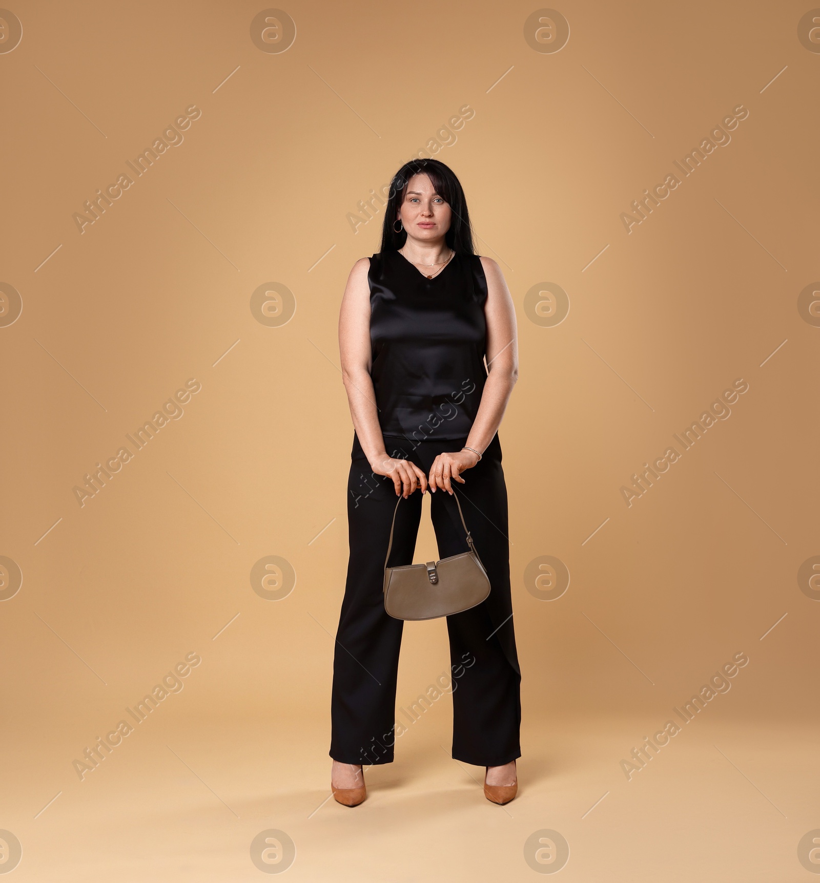 Photo of Elegant plus size model with bag on beige background. Overweight