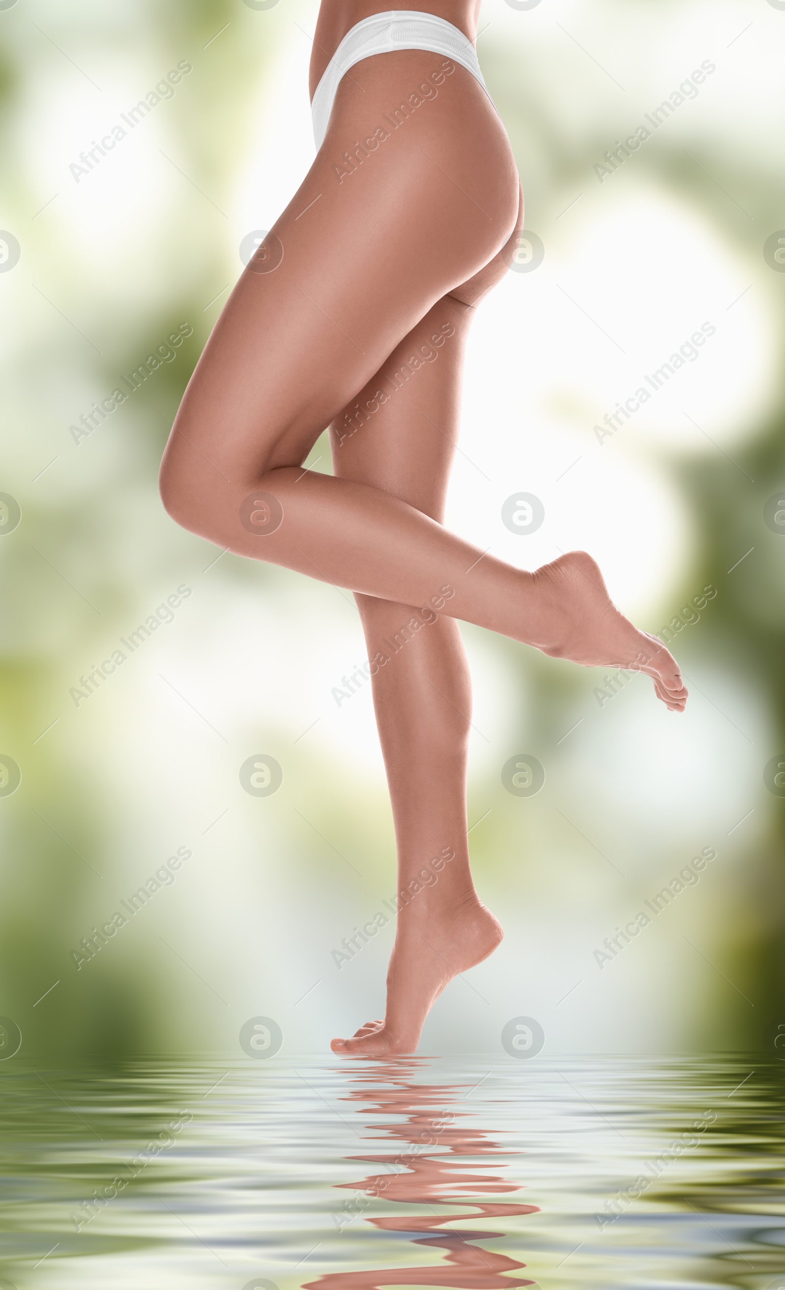 Image of Epilation. Woman showing her legs with smooth soft skin against blurred green background, closeup