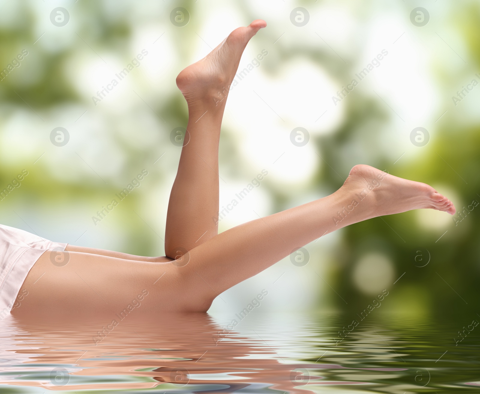 Image of Epilation. Woman showing her legs with smooth soft skin against blurred green background, closeup