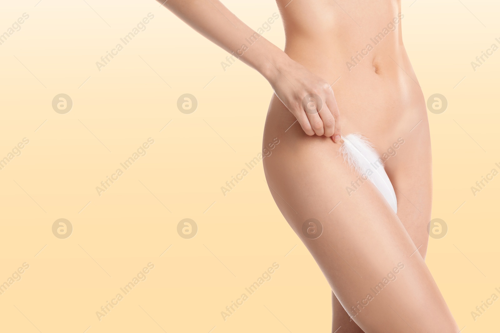 Image of Woman with feather showing smooth skin on beige background, closeup. Bikini epilation