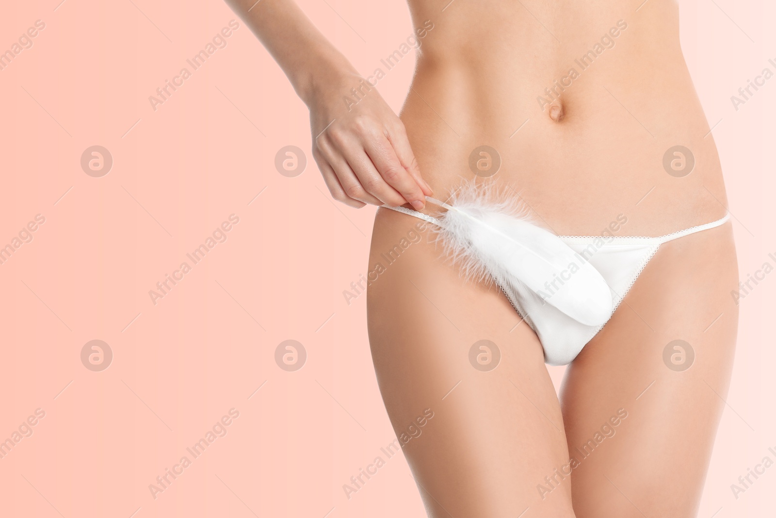 Image of Woman with feather showing smooth skin on pink background, closeup. Bikini epilation