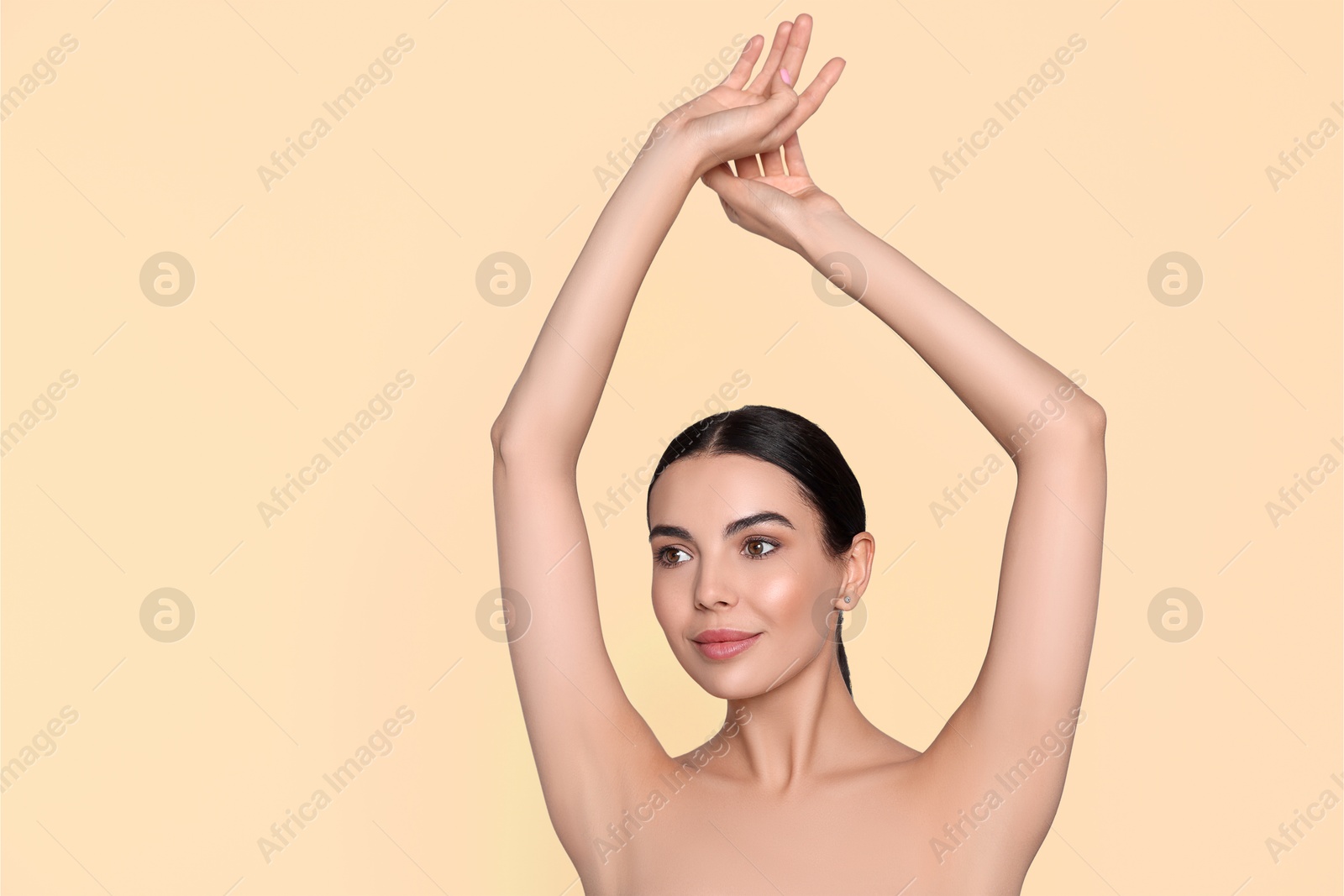 Image of Young woman showing hairless armpits after epilation procedure on dark beige background. Space for text