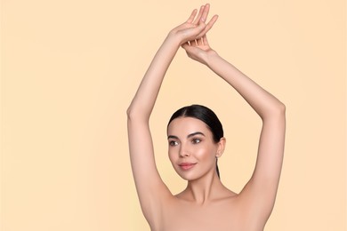 Young woman showing hairless armpits after epilation procedure on dark beige background. Space for text