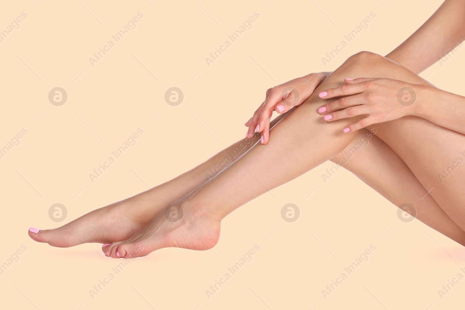 Image of Young woman showing legs with smooth skin after epilation procedure on dark beige background, closeup