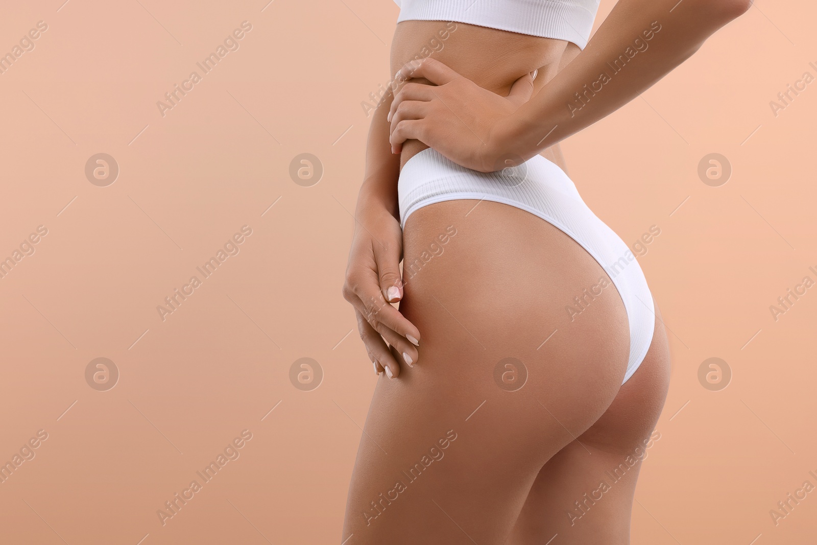 Image of Young woman showing smooth skin after epilation procedure on peach color background, closeup. Space for text