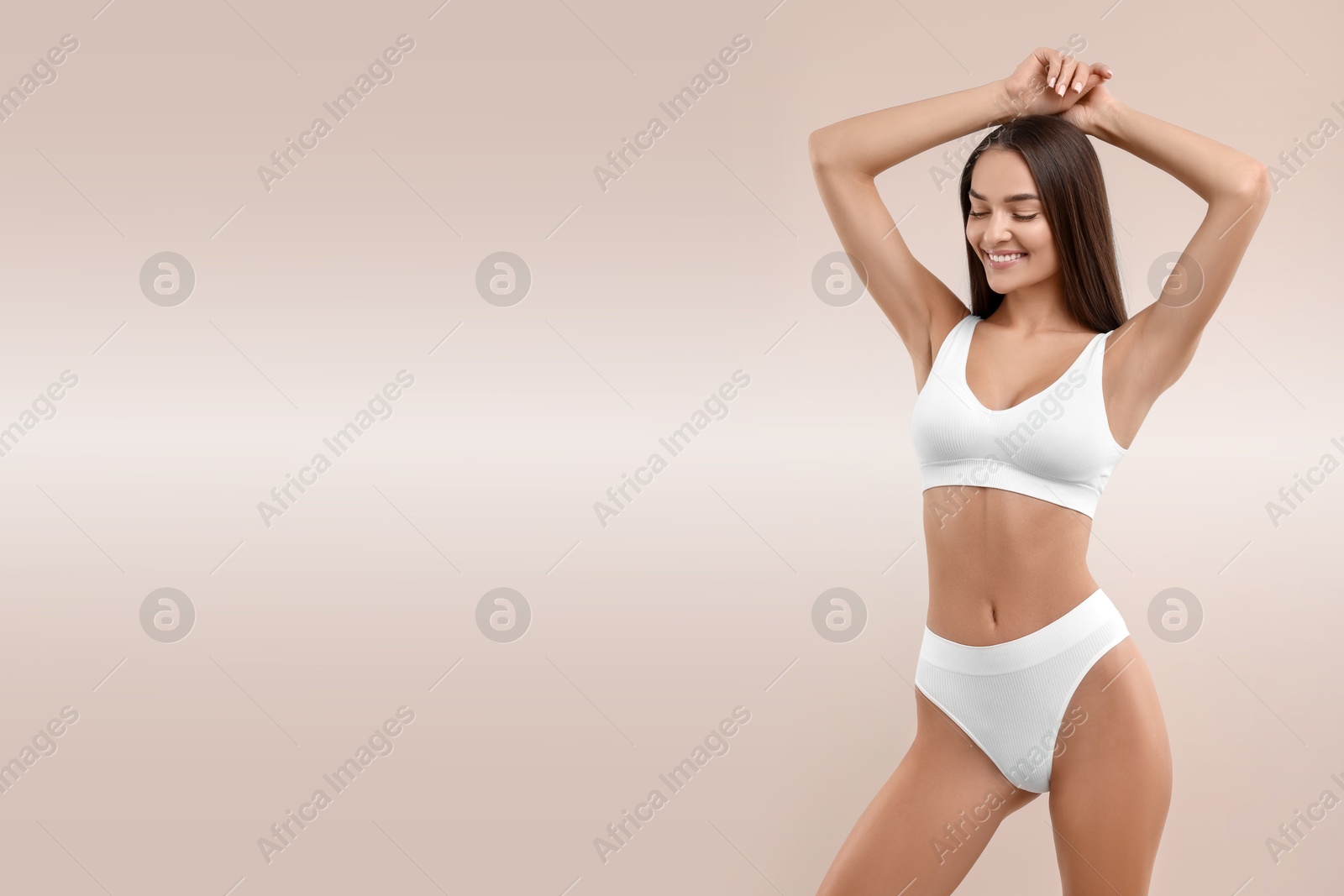 Image of Young woman in white underwear with smooth skin after epilation procedure on pink beige background. Space for text