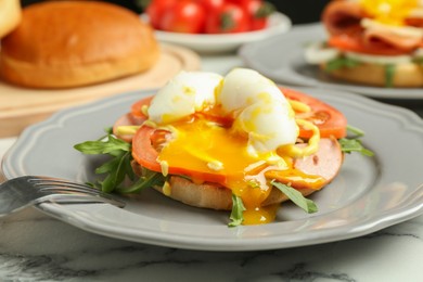 Photo of Tasty brunch. Poached egg, ham, tomato, arugula and bun on white marble table, closeup