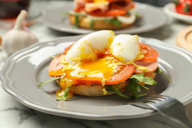 Photo of Tasty brunch. Poached egg, ham, tomato, arugula and bun on white marble table, closeup