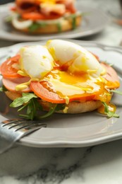 Photo of Tasty brunch. Poached egg, ham, tomato, arugula and bun on white marble table, closeup