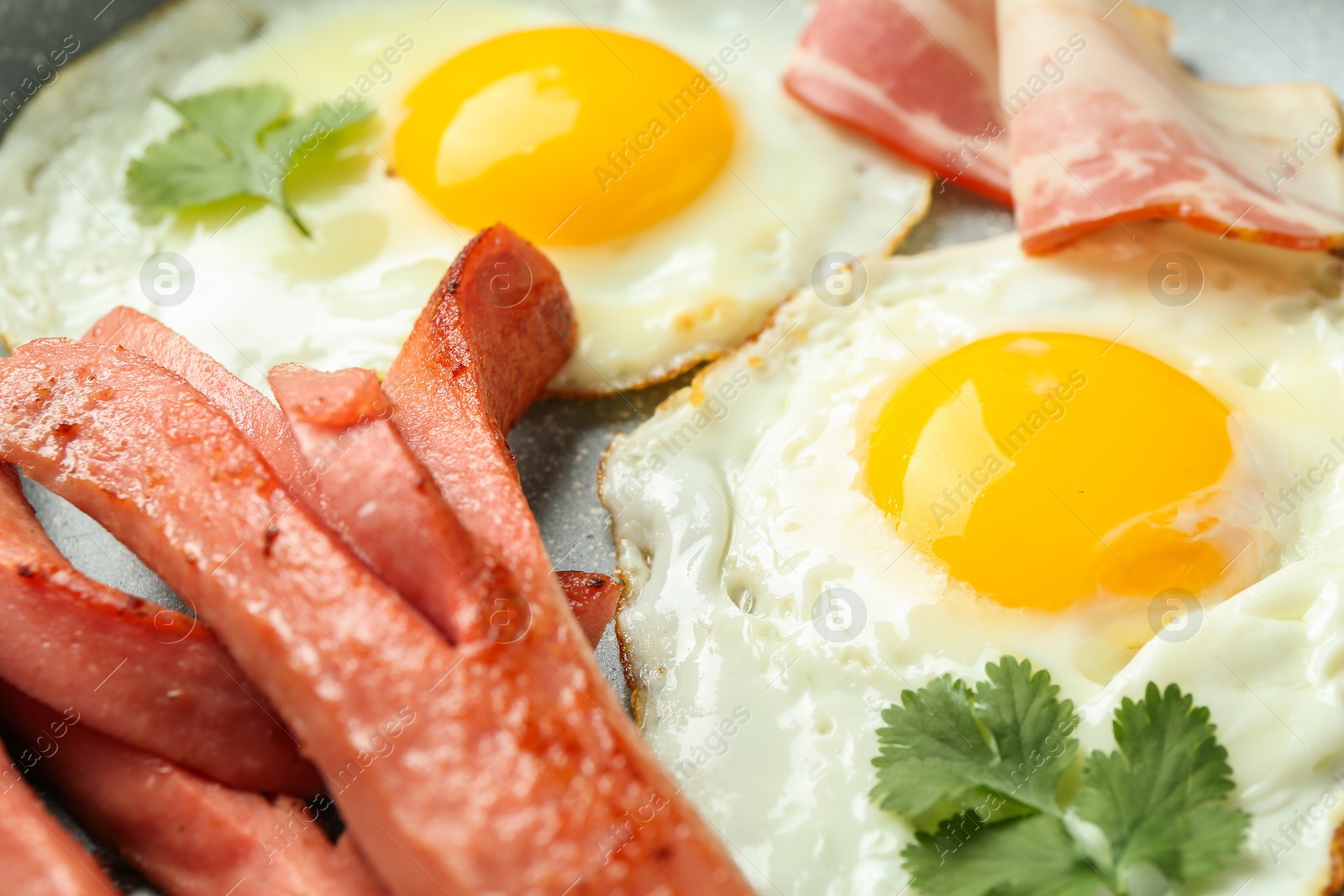 Photo of Tasty brunch. Fried eggs, sausages and bacon on frying pan, closeup