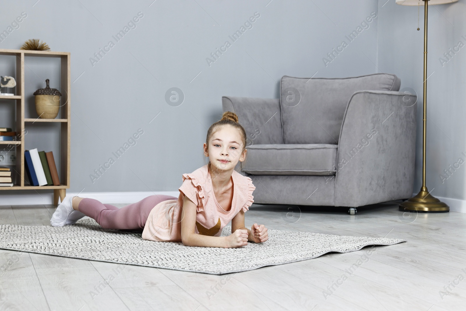 Photo of Little girl doing plank exercise at home. Morning routine