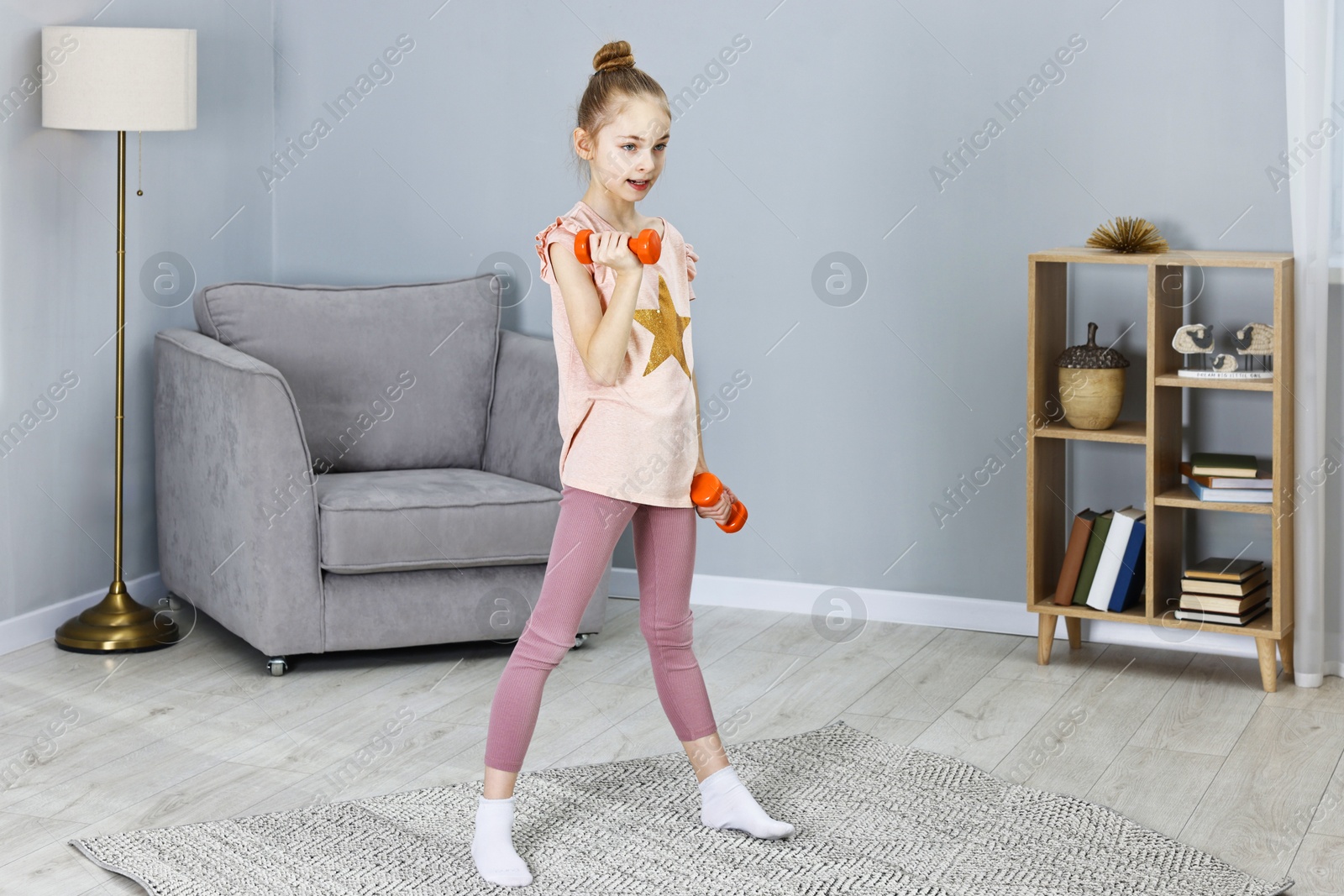 Photo of Little girl exercising with dumbbells at home. Morning routine