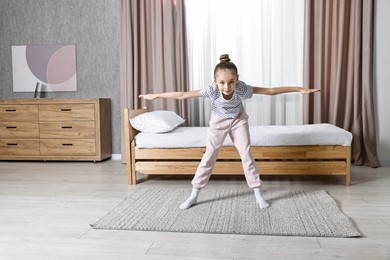 Photo of Little girl exercising at home. Morning routine