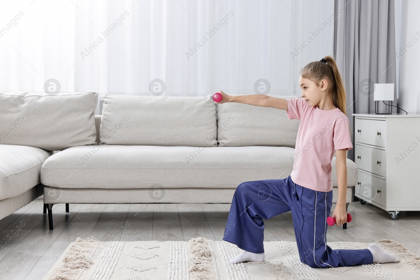 Photo of Little girl exercising with dumbbells at home, space for text. Morning routine