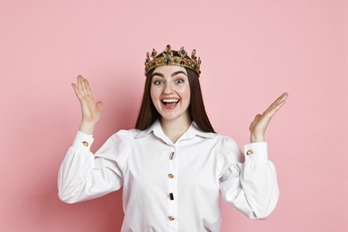 Happy woman in elegant crown on pink background