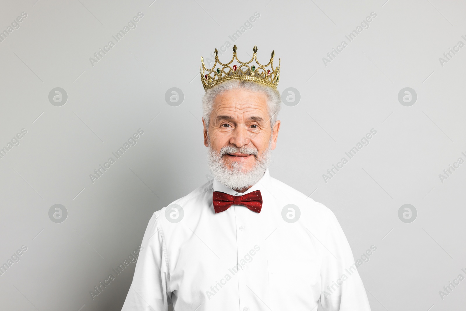 Photo of Senior man wearing luxury crown on grey background