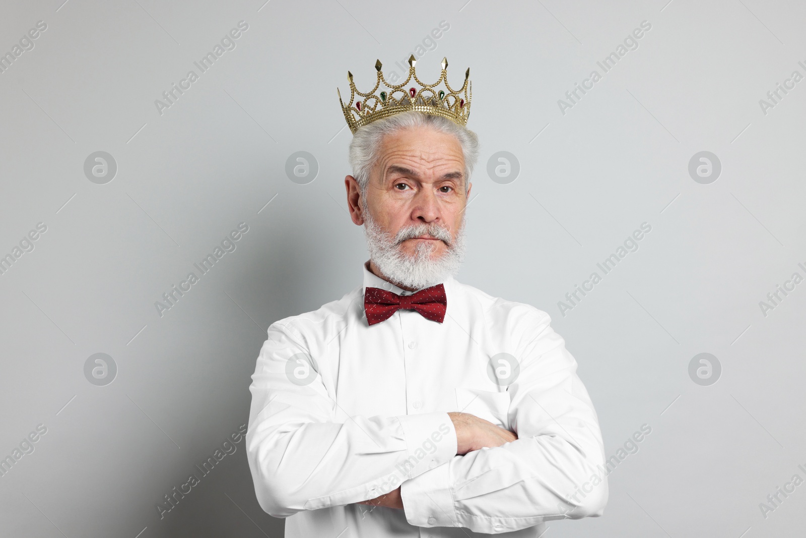 Photo of Senior man wearing luxury crown on grey background