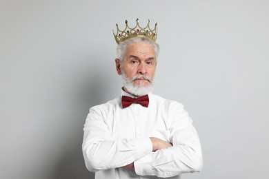 Senior man wearing luxury crown on grey background