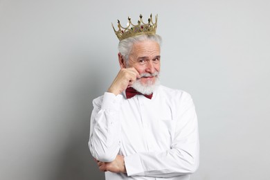 Photo of Senior man wearing luxury crown on grey background