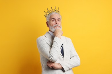 Photo of Senior man wearing luxury crown on orange background