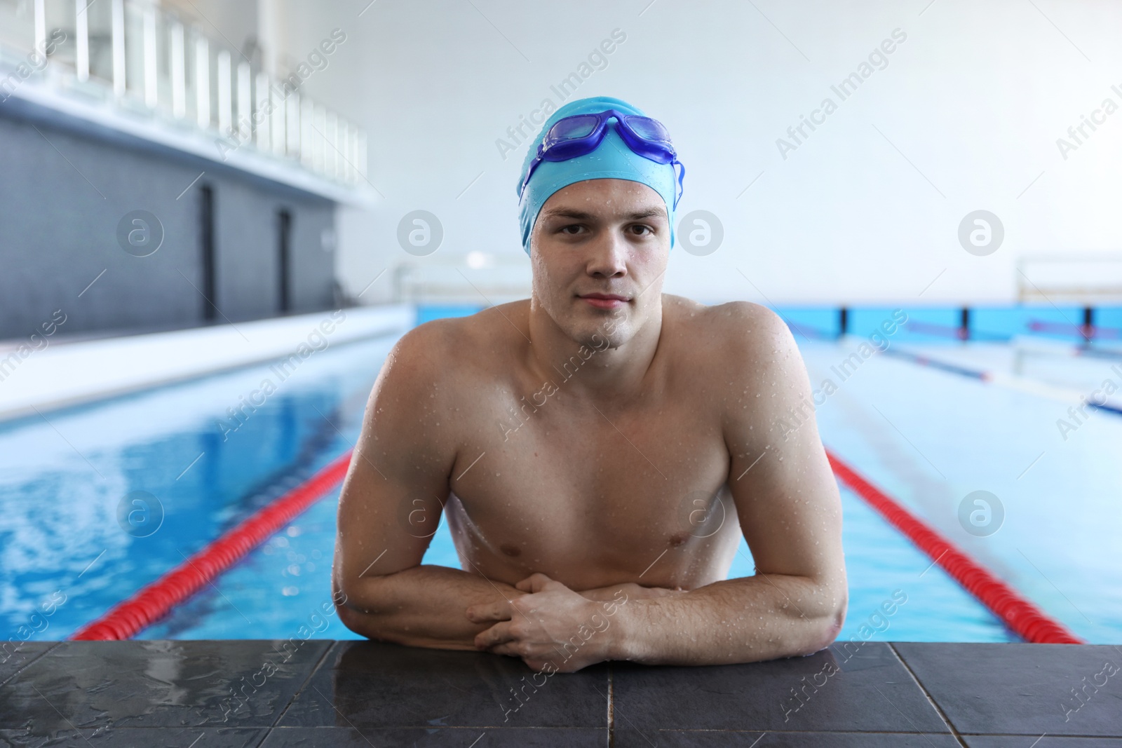 Photo of Young man with cap and goggles in swimming pool indoors