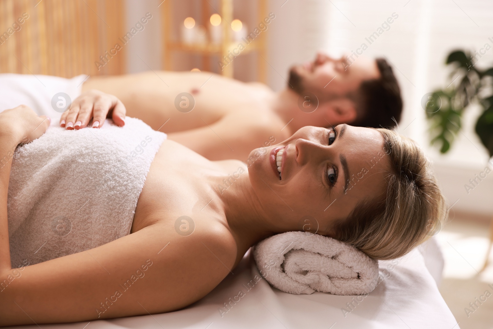 Photo of Happy couple lying on massage tables in spa salon, selective focus