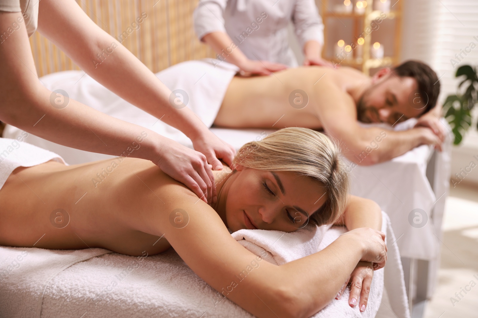 Photo of Couple receiving relaxing massage in spa salon, selective focus