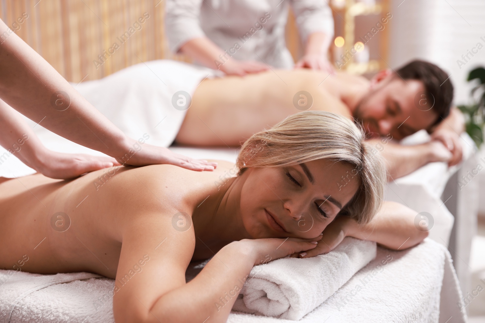 Photo of Couple receiving relaxing massage in spa salon, selective focus