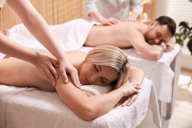 Photo of Couple receiving relaxing massage in spa salon, selective focus