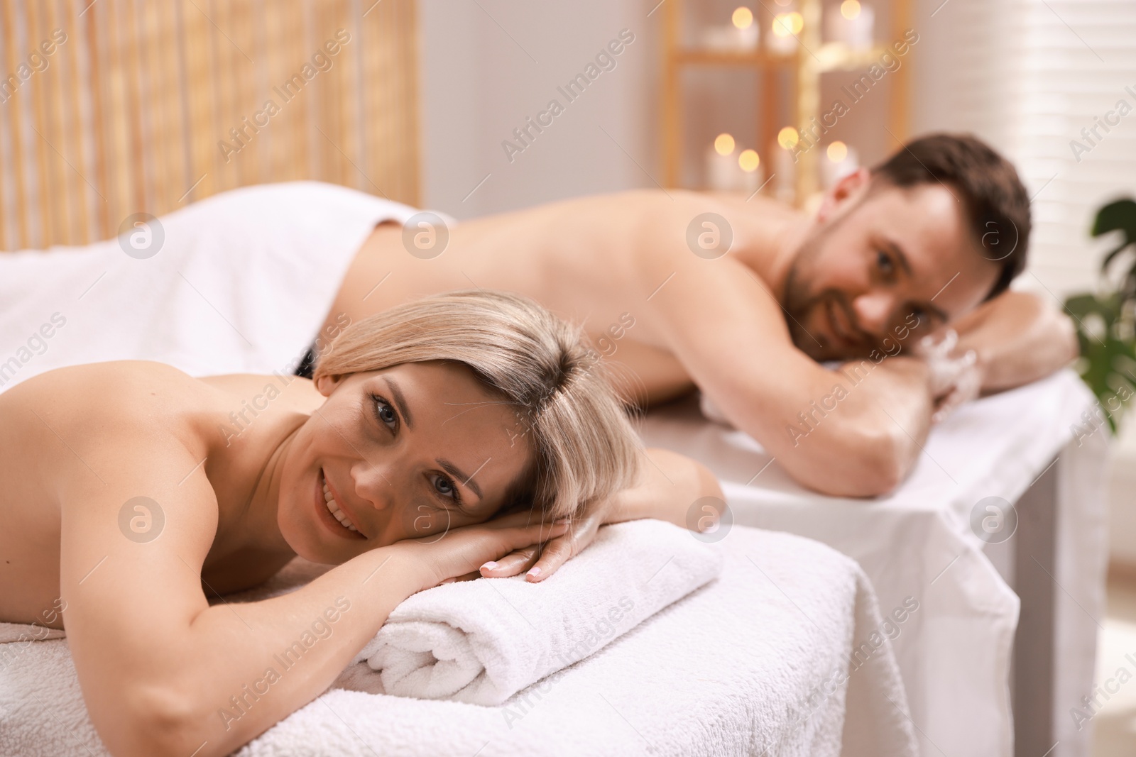 Photo of Happy couple lying on massage tables in spa salon, selective focus