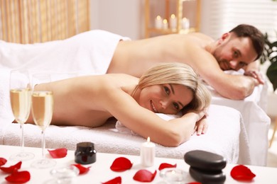 Happy couple lying on massage tables in spa salon, selective focus