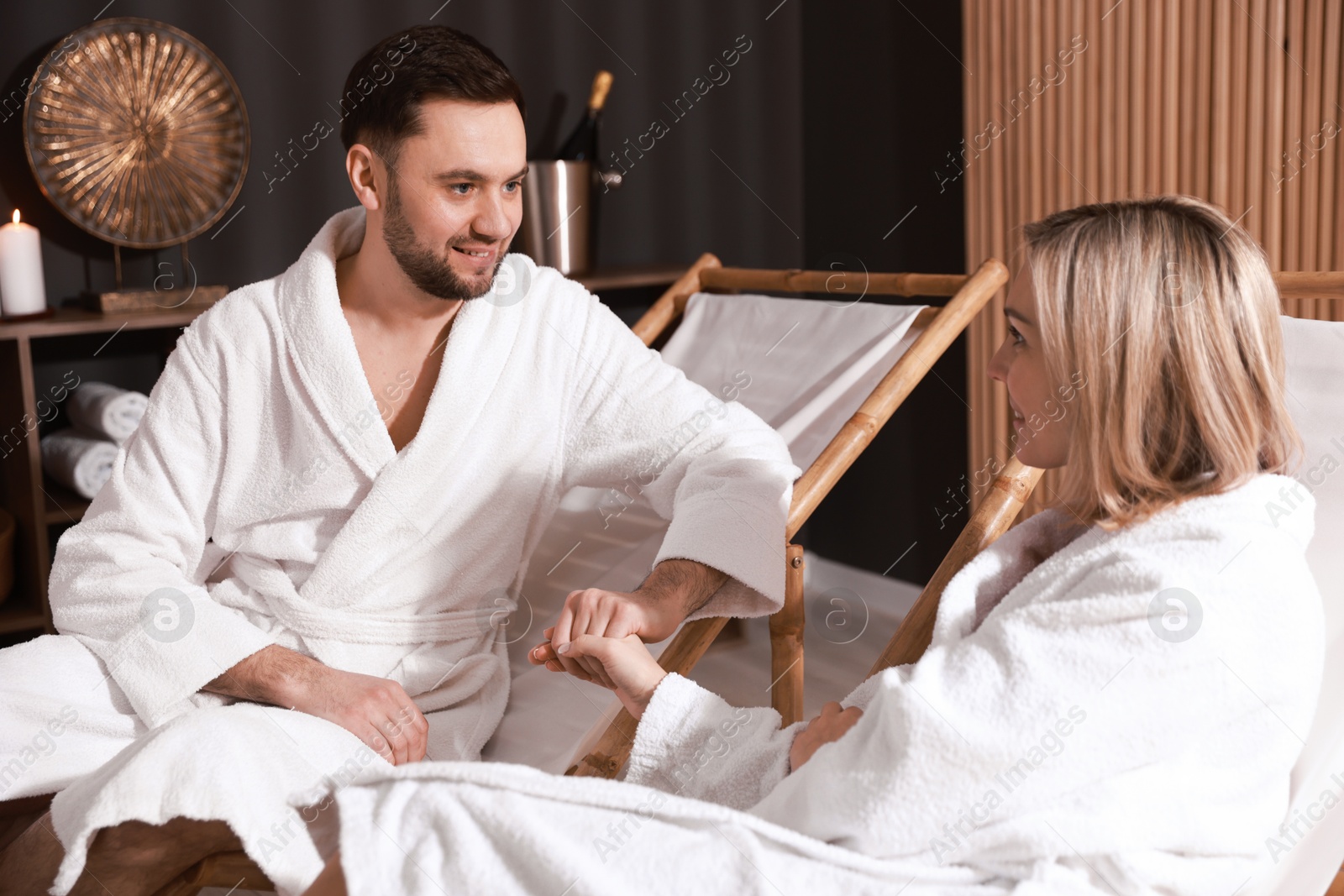 Photo of Happy couple in bathrobes relaxing in spa salon