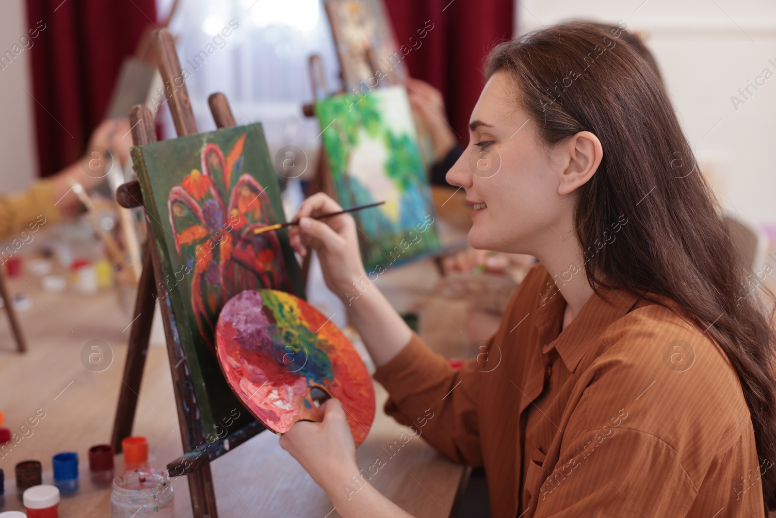 Photo of Smiling woman learning to draw with brush at table in class