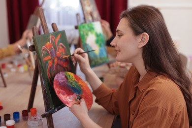 Smiling woman learning to draw with brush at table in class