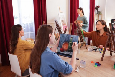 Group of women learning to draw at wooden table in class