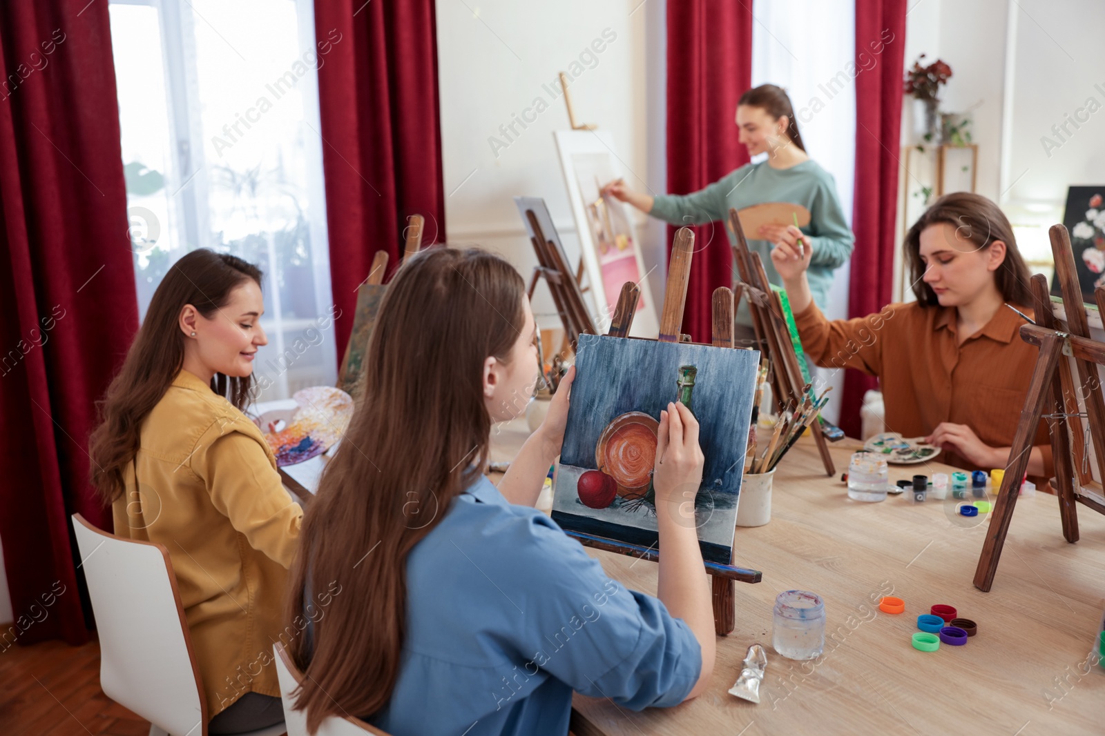 Photo of Group of women learning to draw at wooden table in class