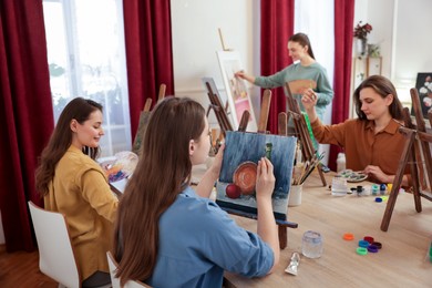 Group of women learning to draw at wooden table in class