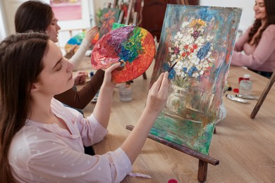 Photo of Group of women learning to draw at wooden table in class