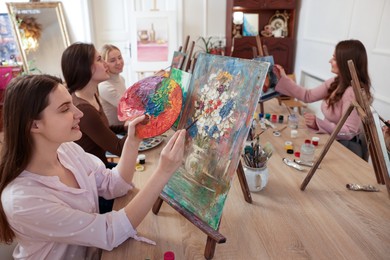 Group of women learning to draw at wooden table in class