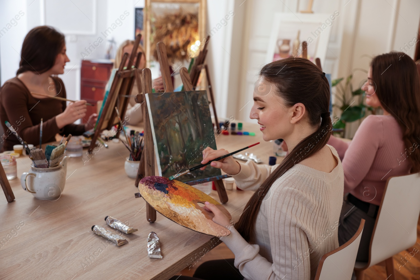 Photo of Group of women learning to draw at wooden table in class