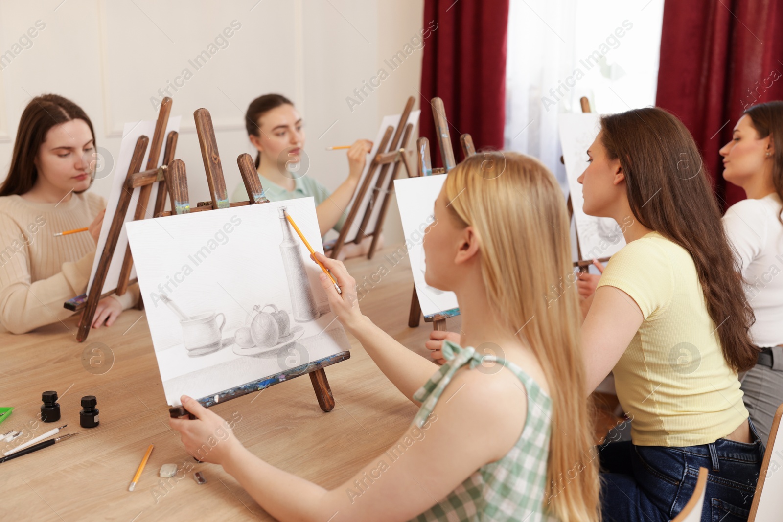 Photo of Group of women learning to draw at wooden table in class