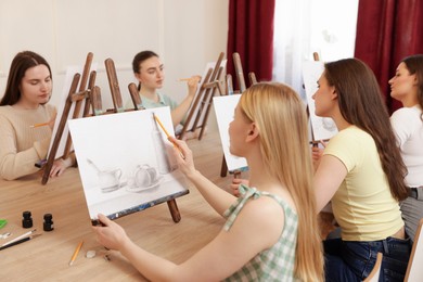 Group of women learning to draw at wooden table in class