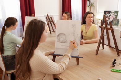 Photo of Group of women learning to draw at wooden table in class