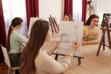 Photo of Group of women learning to draw at wooden table in class