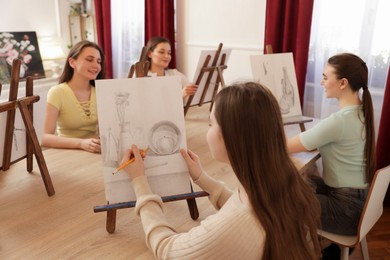 Group of women learning to draw at wooden table in class