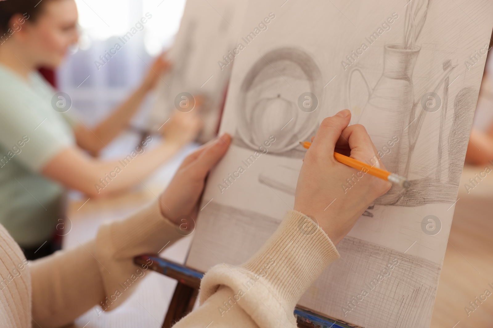 Photo of Woman with pencil learning to draw at table on blurred background, closeup