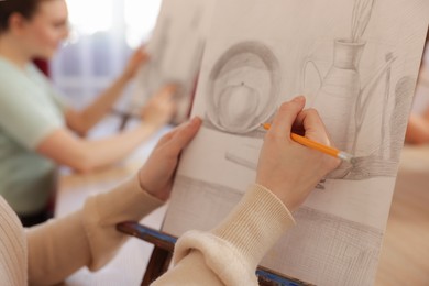 Woman with pencil learning to draw at table on blurred background, closeup